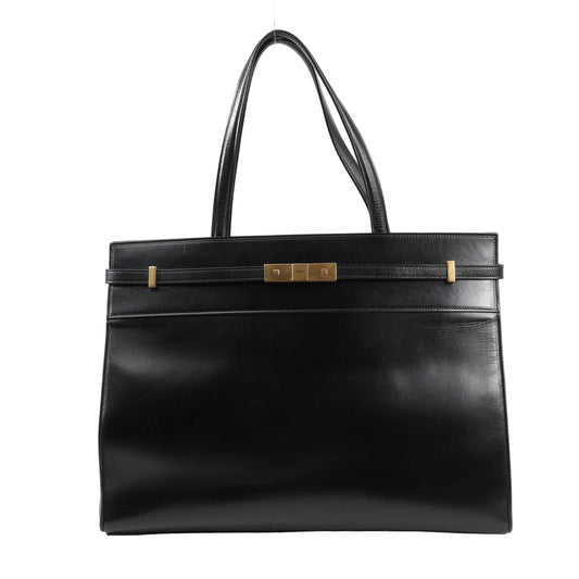 Front view of Saint Laurent Paris Manhattan Tote Bag in black smooth leather, featuring structured silhouette, slim leather strap detail, gold-tone square clasp, and dual leather shoulder handles.