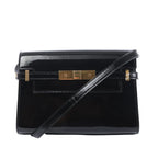 Saint Laurent Manhattan shoulder bag in black patent leather with a slim strap, structured flap and gold-tone clasp hardware.