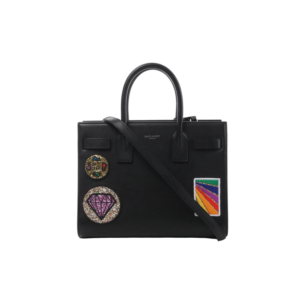 Black Saint Laurent Sac de Jour Small leather handbag with top handles, long shoulder strap and colorful decorative patches on the front.