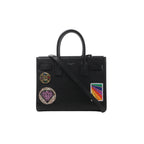 Black Saint Laurent Sac de Jour Small leather handbag with top handles, long shoulder strap and colorful decorative patches on the front.
