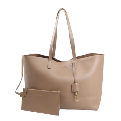Saint Laurent Paris beige leather shopping tote bag with gold YSL charm, long handles, and matching detachable zip pouch.