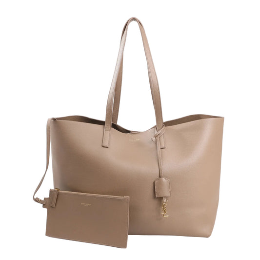 Saint Laurent Paris beige leather shopping tote bag with gold YSL charm, long handles, and matching detachable zip pouch.