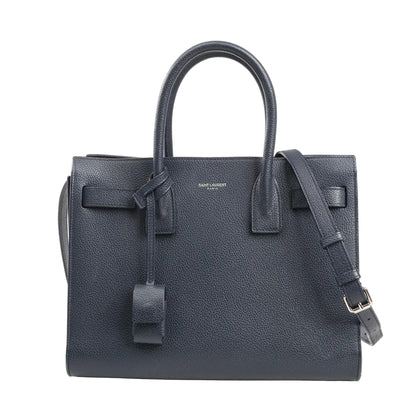 Saint Laurent Sac de Jour Baby 2Way handbag in navy blue grained leather featuring dual top handles, adjustable shoulder strap, and minimal silver logo detailing.