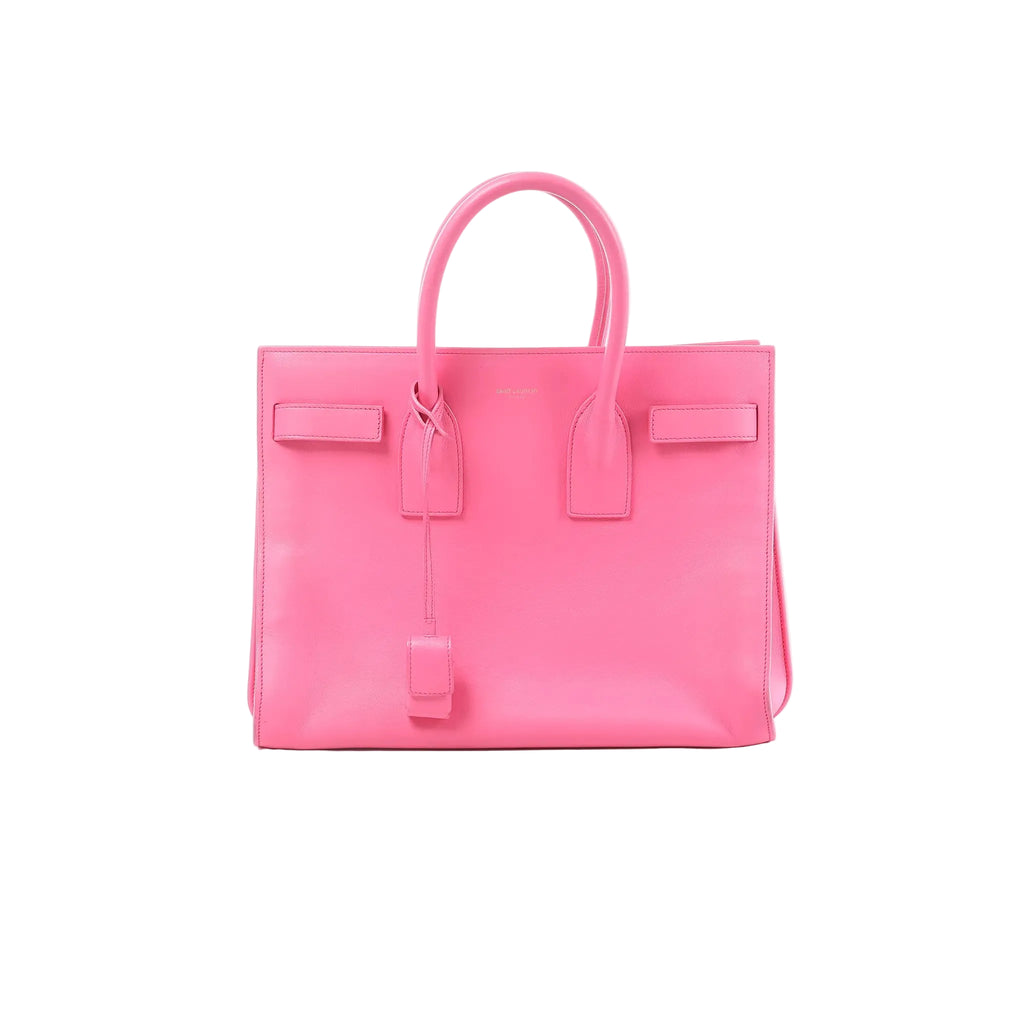 Saint Laurent Sac de Jour pink leather structured handbag with top handles, hanging clochette, and small gold logo text on front, on white background