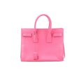 Saint Laurent Sac de Jour pink leather structured handbag with top handles, hanging clochette, and small gold logo text on front, on white background
