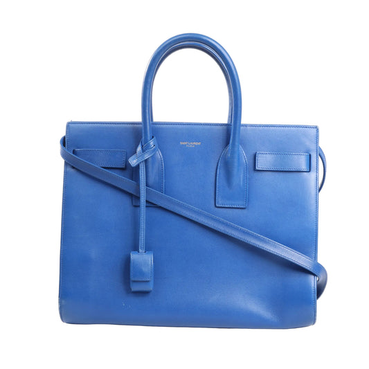 Saint Laurent Paris Sac de Jour 2way handbag in smooth blue leather, featuring dual top handles, a long crossbody strap, and structured silhouette with minimal gold branding.