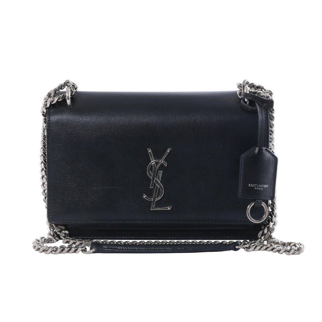Saint Laurent Sunset black leather crossbody bag with silver-tone YSL logo, chain strap, flap front and leather tag.