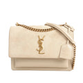 Front view of a beige Saint Laurent Sunset Medium shoulder bag with a suede flap, gold YSL logo, gold chain strap with a beige leather shoulder pad, and smooth leather body on a white background.