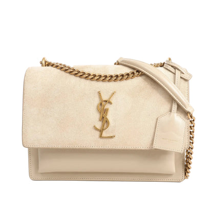 Front view of a beige Saint Laurent Sunset Medium shoulder bag with a suede flap, gold YSL logo, gold chain strap with a beige leather shoulder pad, and smooth leather body on a white background.
