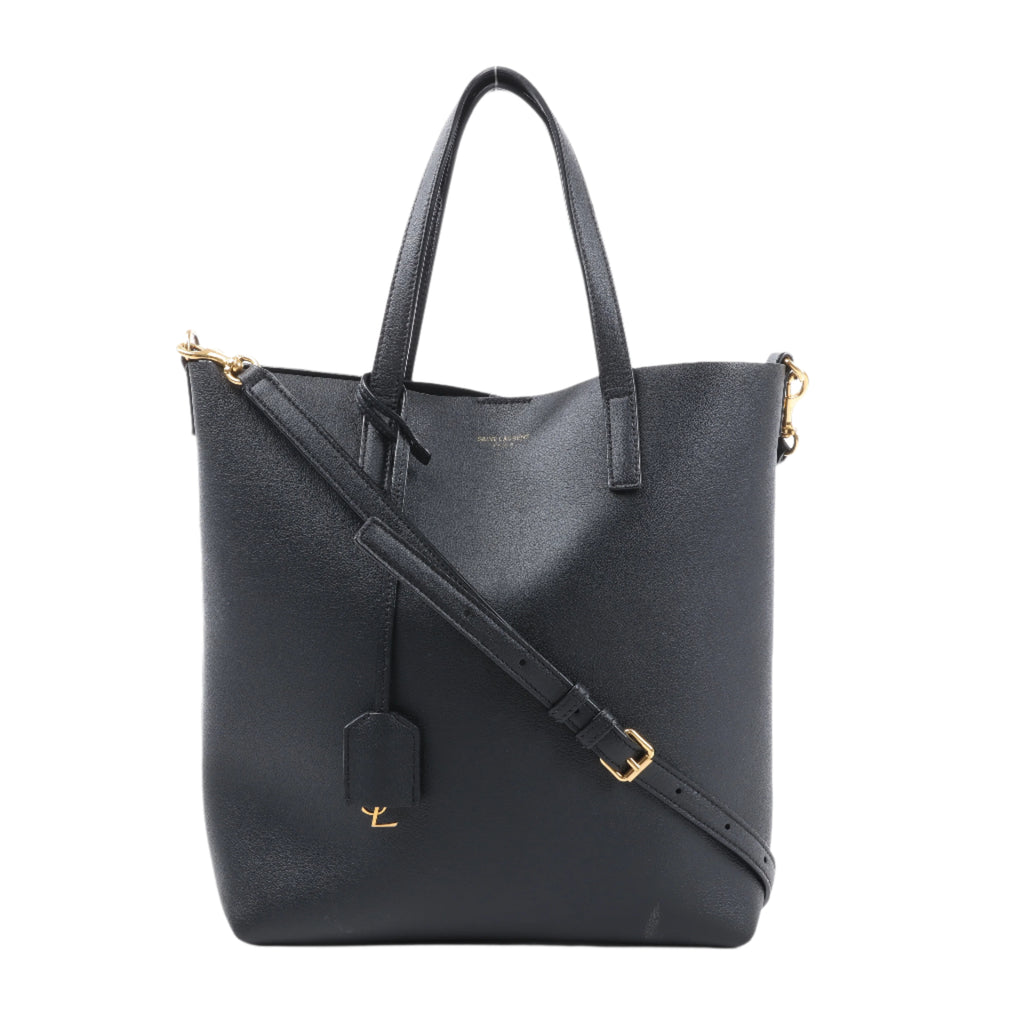 Black leather tote bag with gold accents on a white background