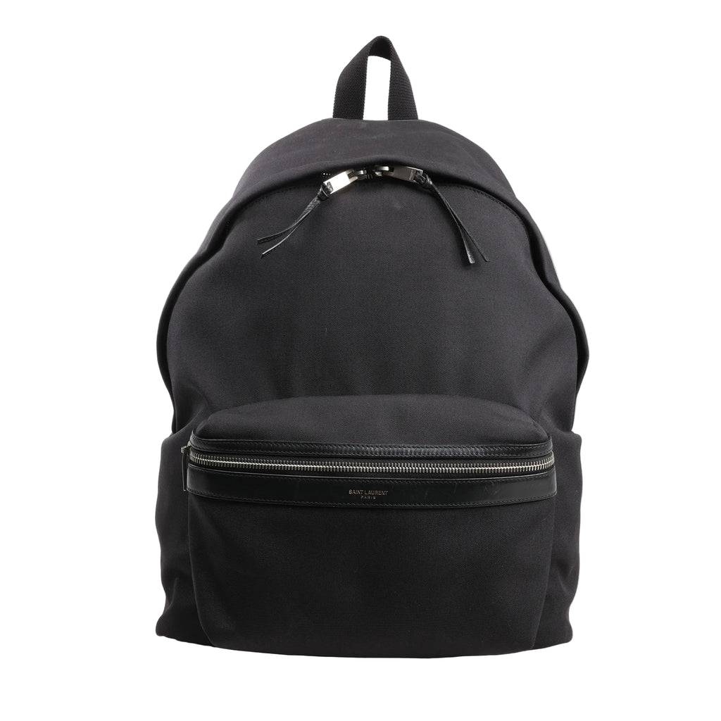 Saint Laurent Paris black canvas and leather backpack model 435988 featuring a front zip pocket with leather trim, dual zipper pulls, and a top carry handle, displayed upright against a white background.