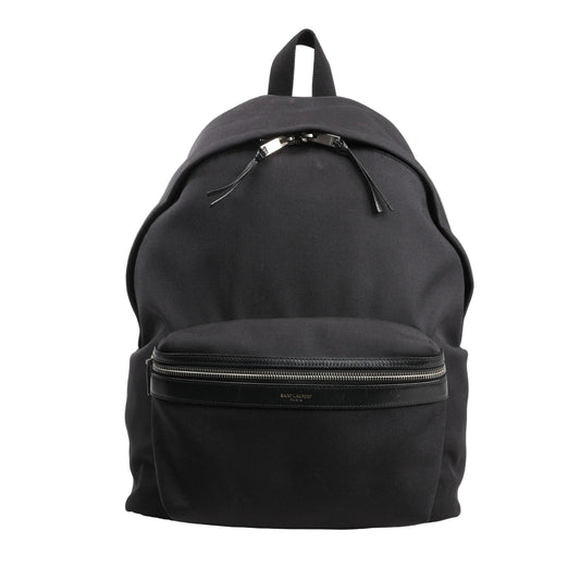 Saint Laurent Paris black canvas and leather backpack model 435988 featuring a front zip pocket with leather trim, dual zipper pulls, and a top carry handle, displayed upright against a white background.