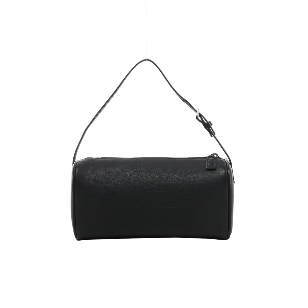 Front view of The Row 90’s black grained leather handbag with an elongated rectangular shape, slim buckled strap and top zip closure.