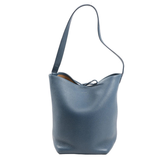 The Row Park Tote Small Shoulder Bag in blue grained leather featuring a slouchy, unstructured silhouette, single flat shoulder strap, and open top with tie closure, shown on a white background.