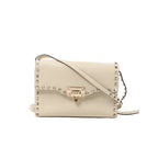 Beige Valentino Garavani Rockstud crossbody bag with grainy leather, pyramid studs, front flap, metal clasp and slender shoulder strap.