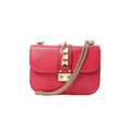 Pink Valentino Rockstud Glam Lock leather crossbody bag with gold-tone pyramid stud strap, front lock closure, and gold chain strap on white background.