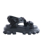 Black Valentino Garavani Rockstud sandal with leather and fabric straps, buckle closures and a chunky platform sole with pyramid-shaped studs on a white background.