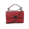 Valentino Rockstud Spike red quilted leather crossbody bag with black-tone studs, chain strap, top handle, and front turn-lock closure on white background.
