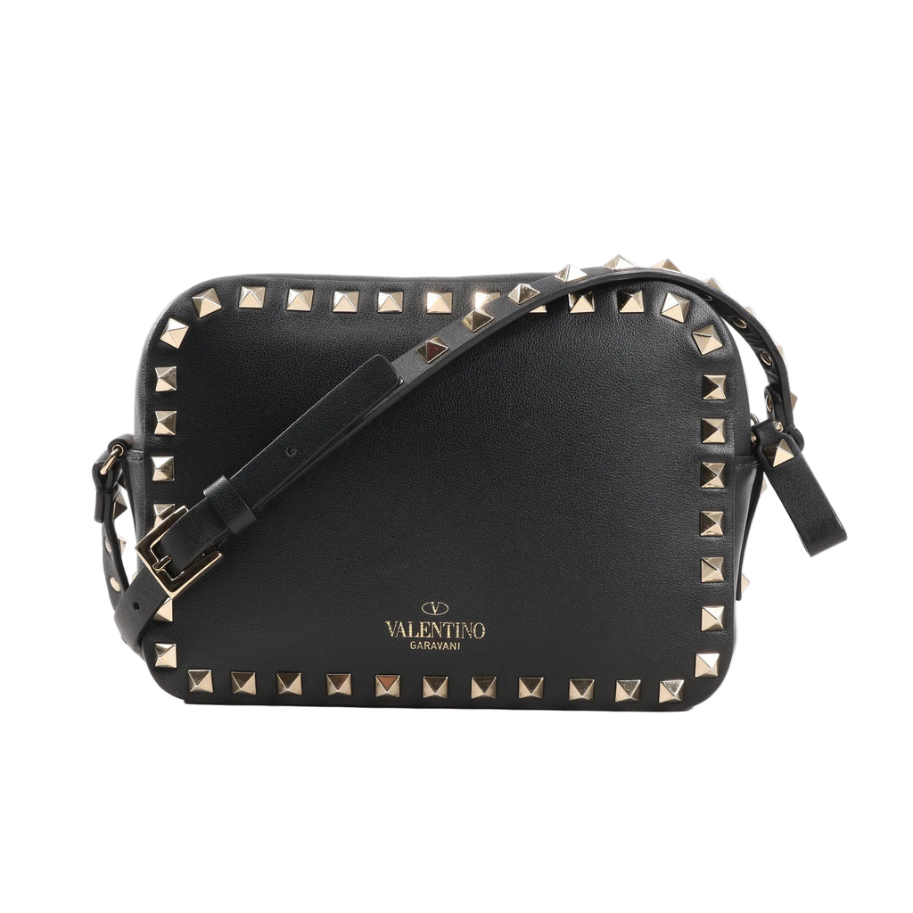 Valentino Garavani Rockstud Crossbody Bag in black leather with gold-tone pyramid stud trim, adjustable shoulder strap, and gold logo detail, displayed against a white background.