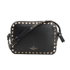 Valentino Garavani Rockstud Crossbody Bag in black leather with gold-tone pyramid stud trim, adjustable shoulder strap, and gold logo detail, displayed against a white background.