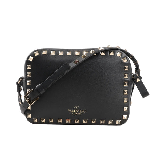 Valentino Garavani Rockstud Crossbody Bag in black leather with gold-tone pyramid stud trim, adjustable shoulder strap, and gold logo detail, displayed against a white background.
