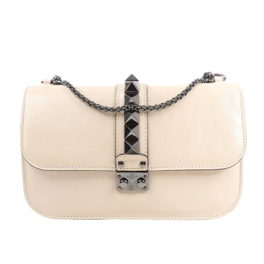 Beige handbag with a decorative chain and clasp on a white background