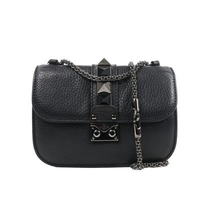 Valentino Rockstud Glam Lock shoulder bag in black grained leather with pyramid stud accents, flap closure with metal lock, and silver-tone chain strap against a white background.