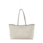 Valentino Garavani Rockstud ecru grained leather shoulder bag with slim shoulder straps, silver-tone stud trim, and structured open-top silhouette on white background.