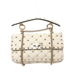Front view of a beige quilted Valentino Garavani bag with gold-tone pyramid studs, a studded top handle, chain shoulder strap and rectangular turn-lock.