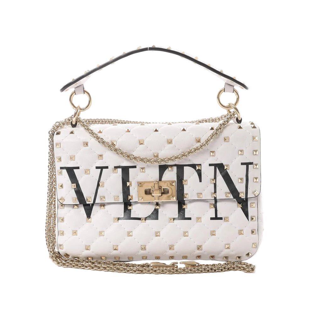 White Valentino Rockstud Spike VLTN quilted leather shoulder bag with gold stud detailing, gold chain strap, top handle, and turn-lock closure on white background