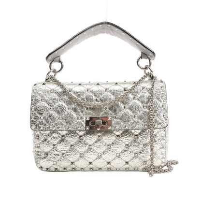 Valentino Garavani Rockstud Spike 2Way shoulder bag in metallic silver quilted leather, featuring pyramid stud detailing, a top handle, turn-lock closure, and silver chain strap, shown on a white background.