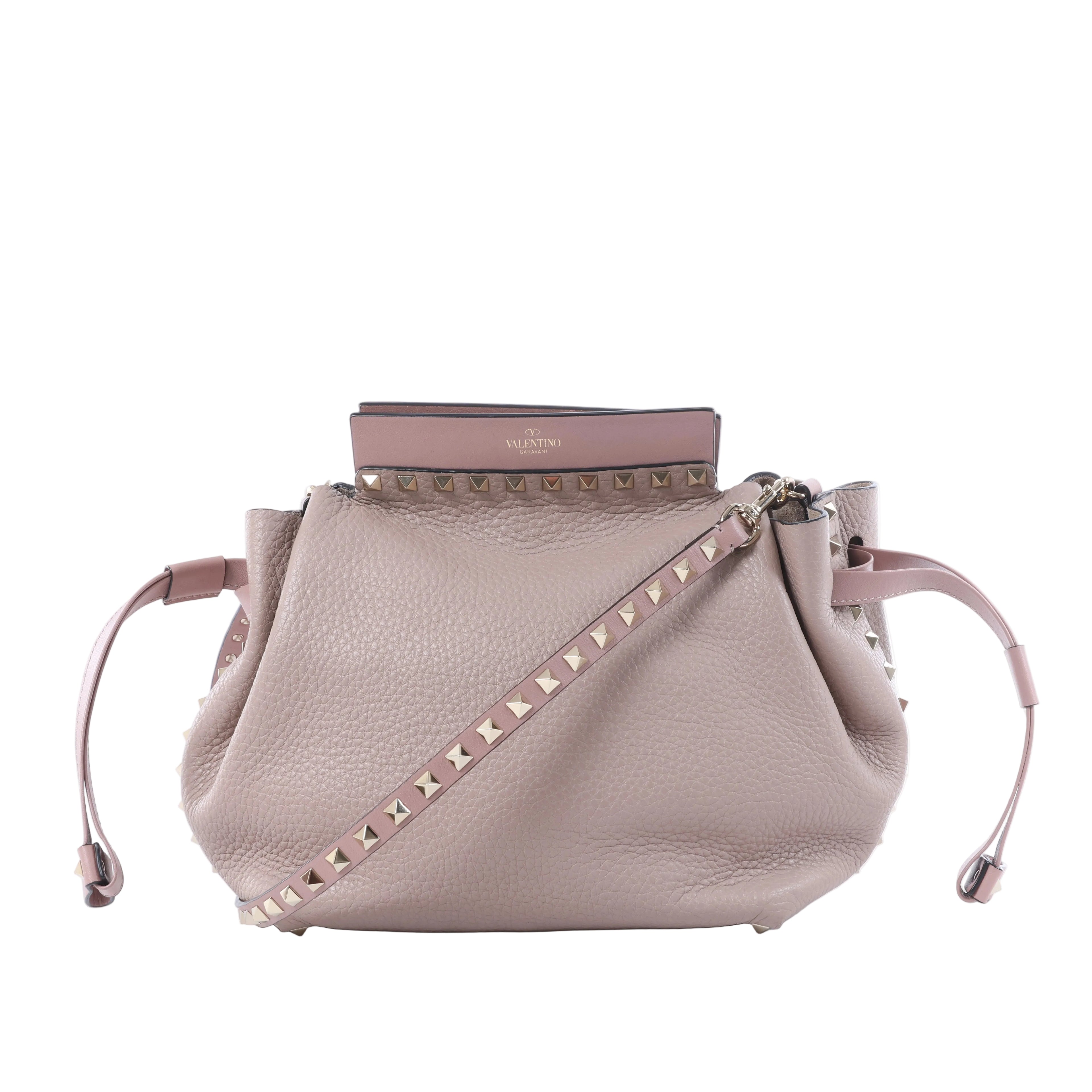 Valentino Garavani Rockstud pink leather crossbody bag with pyramid stud trim, studded shoulder strap and drawstring sides.
