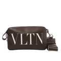 Valentino Garavani VLTN shoulder bag in smooth brown leather with large white logo print, detachable strap, zip closure, and rectangular structured shape against a white background.