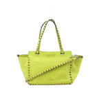 Valentino Garavani Rockstud yellow leather 2-way handbag with gold-tone pyramid studs, double top handles, and detachable shoulder strap on white background