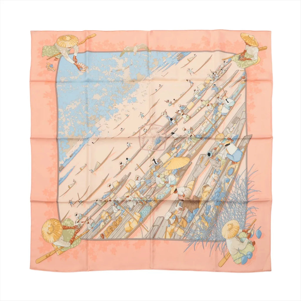 Pink and pale blue Hermès Carré 90 silk scarf laid flat with an illustrated Lake Inlé floating market scene of boats and figures.