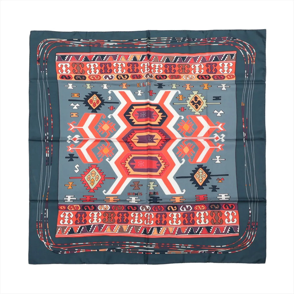 Hermès Carré 90 KILIM silk scarf with gray center, red, orange and cream geometric motifs and a deep teal border.
