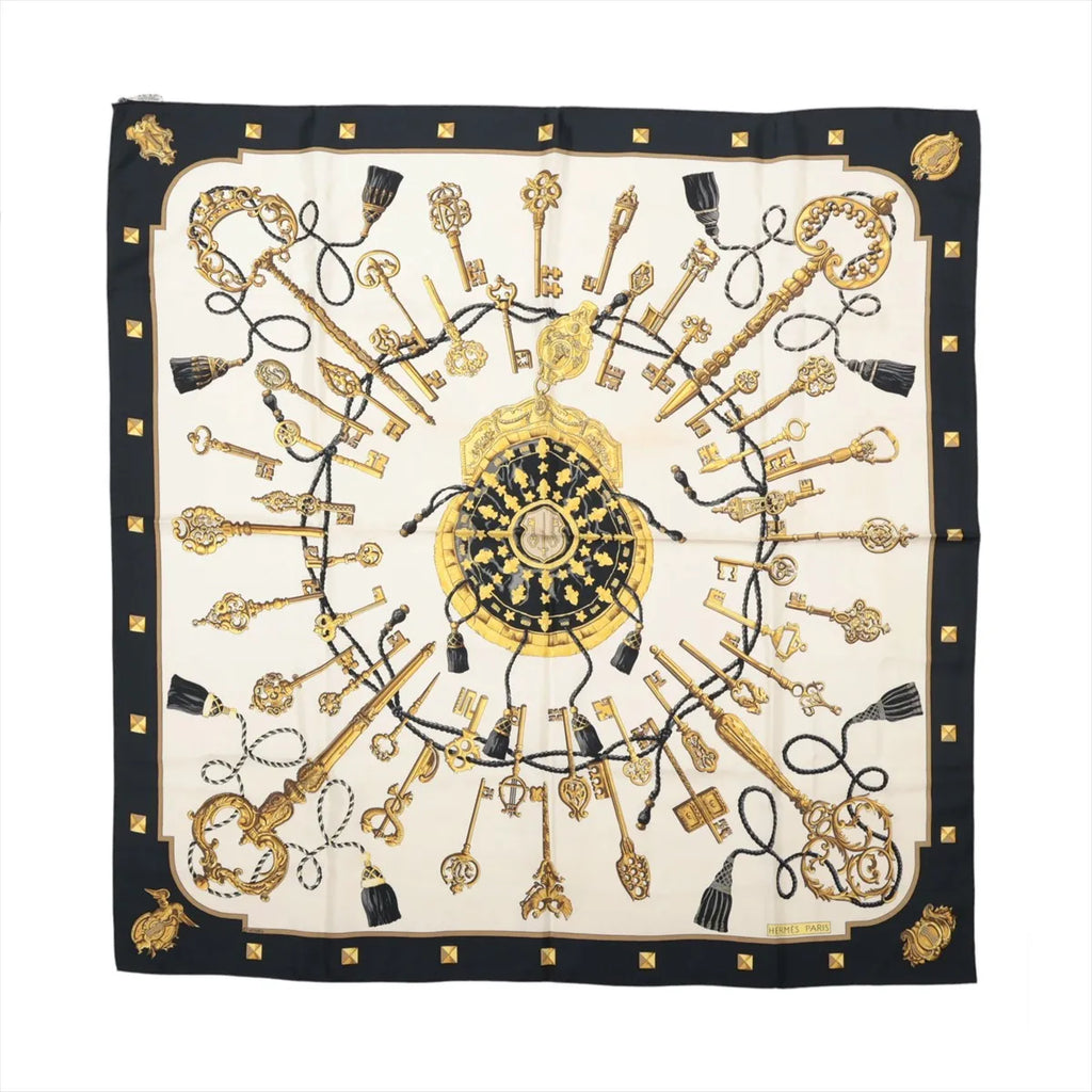 Hermès Carré 90 Les Clés silk scarf with black border, ivory center, ornate gold key motifs, black tassels and gold stud details.