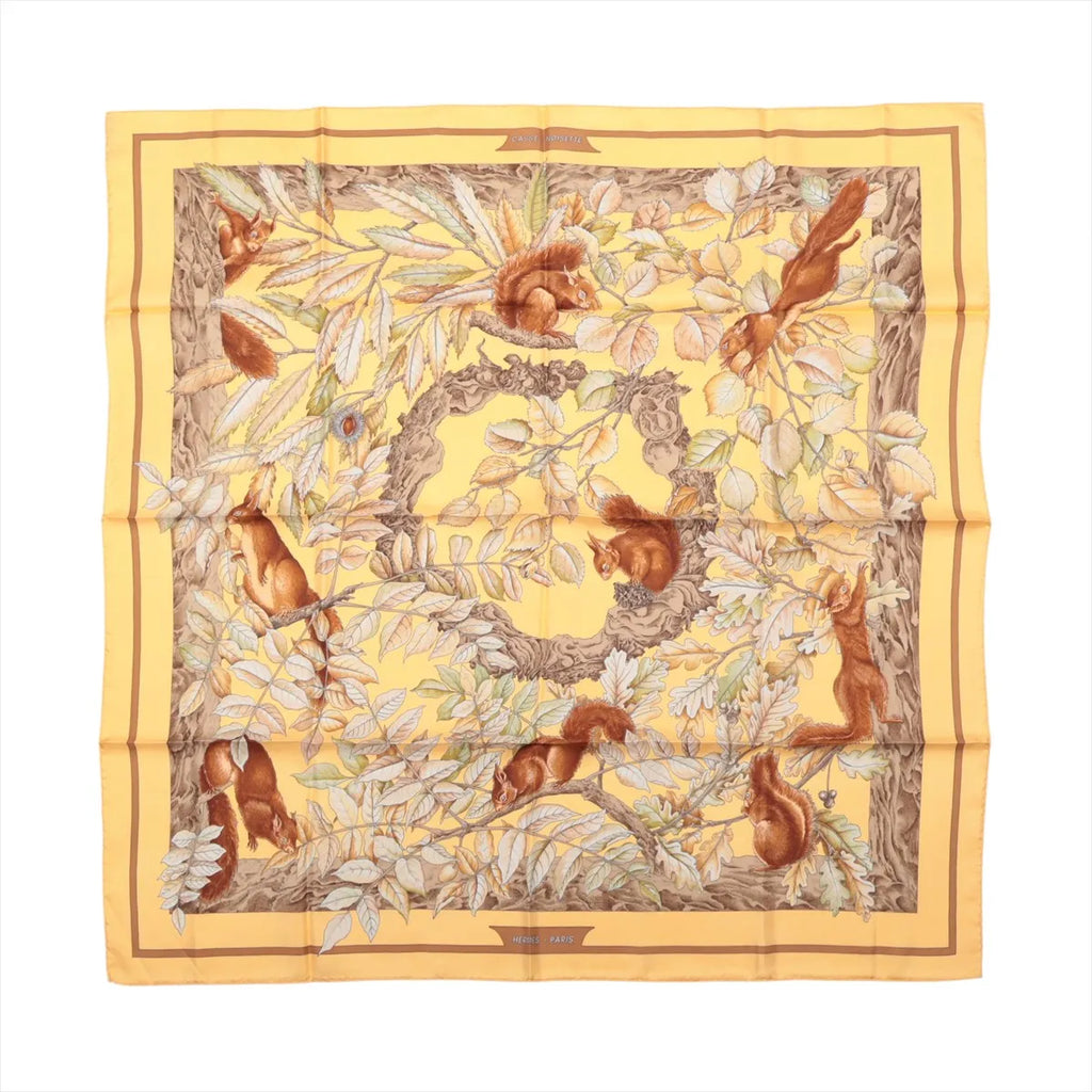 Hermès Carré 90 Casse Noisette yellow silk scarf with red squirrels, leafy branches and brown, cream and green botanical details.