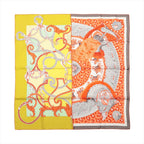 Hermès Carré 90 silk scarf with split yellow and orange design, ornate harness motifs, gray detailing and elaborate feathered ceremonial elements.