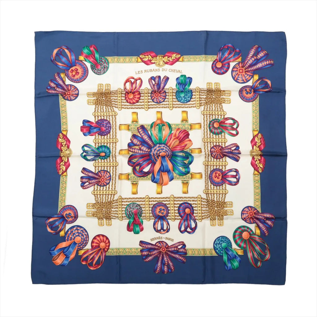 Hermès Carré 90 Les Rubans du Cheval silk scarf with navy border, ivory center, multicolor ribbon rosettes, bows and gold harness motifs.