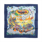 Hermès silk scarf with navy blue border, colorful winged figures, orange and yellow artwork, stars and bold multicolor graphic lettering.